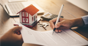 Image features hands of two people signing a trust document