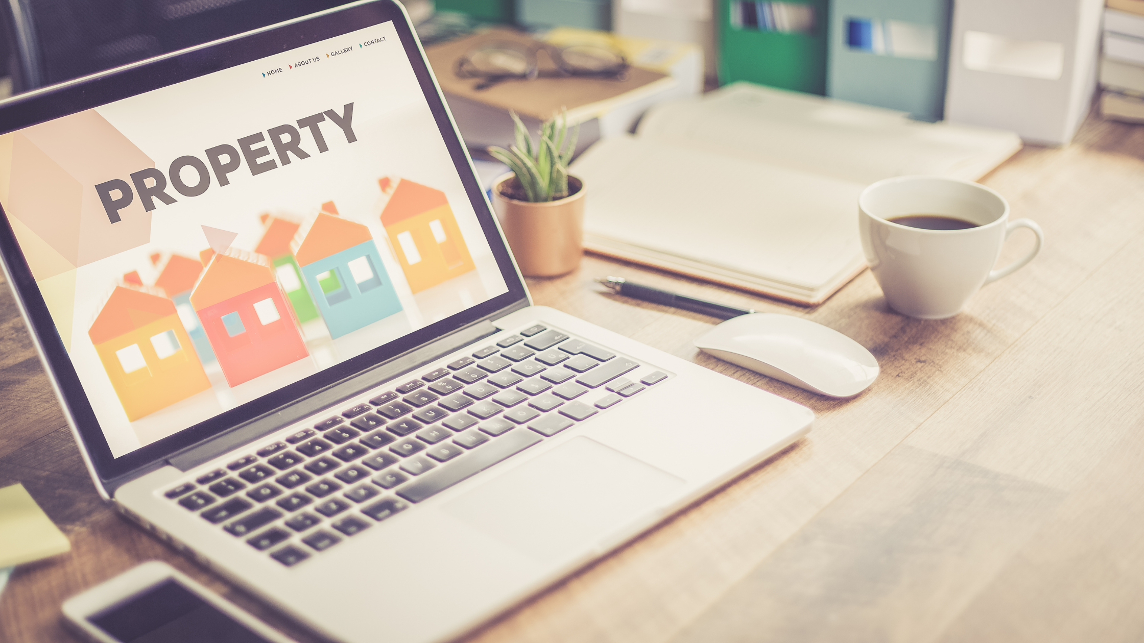 laptop with the words property on it with small colourful illustrated houses